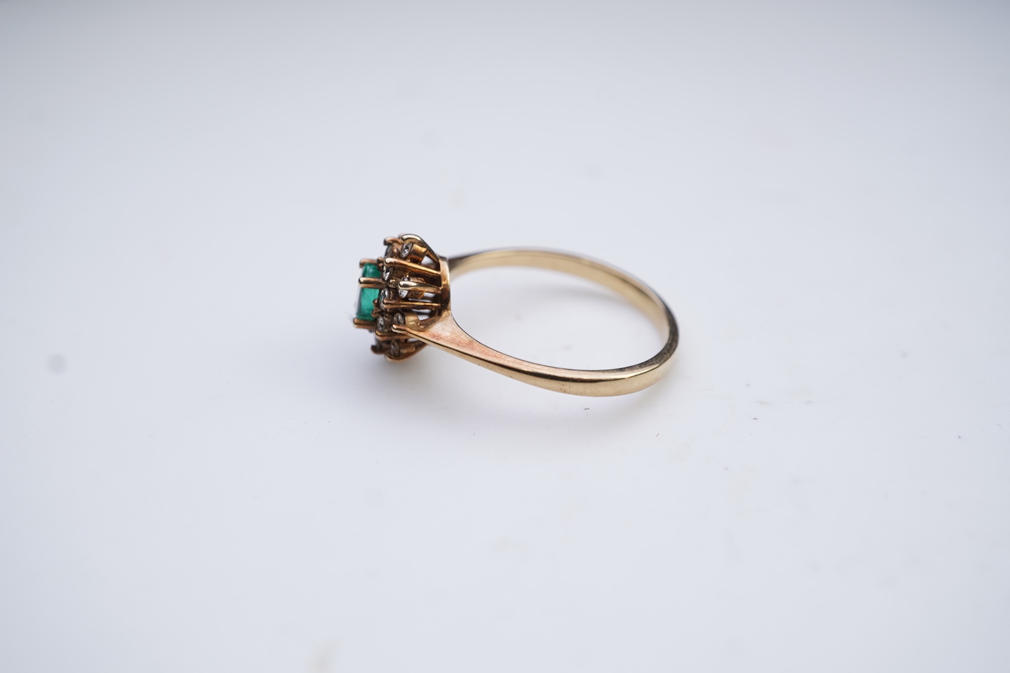 An emerald and diamond cluster ring